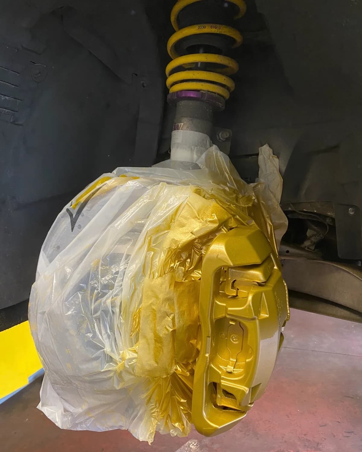 Étrier de frein fraîchement repeint en doré sur un train avant lors d'un service freins